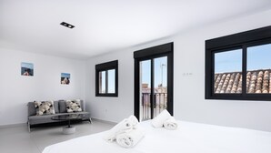 A modern hotel room with a large bed, a grey sofa, and a balcony with a view of the city. - ESTEPONA TOWN CENTRE 2339 (Estepona)
