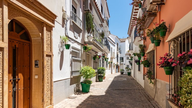 A narrow cobblestone street flanked by buildings with balconies adorned with potted plants. - ESTEPONA TOWN CENTRE 2339 (Estepona)