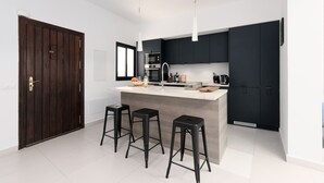 A modern kitchen with dark cabinets, a white countertop, and three black stools. - ESTEPONA TOWN CENTRE 2339 (Estepona)