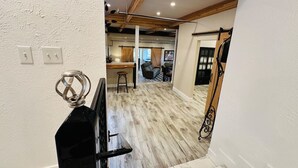 Ein modernes Interieur mit Holzboden, einer Küchenzeile und einer Sitzecke mit Sofa und Sesseln.