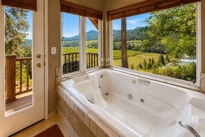A bathroom with a large bathtub, wooden deck outside, and a scenic view of a valley. - Stargaze | Views | Hot Tub | Dogs | BBQ | Firepit (Leavenworth)