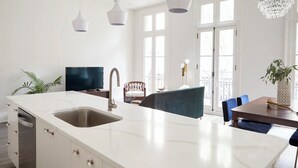 Une cuisine moderne dotée d’un grand îlot central, de meubles blancs et d’un lave-vaisselle encastré.