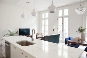 Una cocina moderna con una isla grande, armarios blancos y lavavajillas integrado.