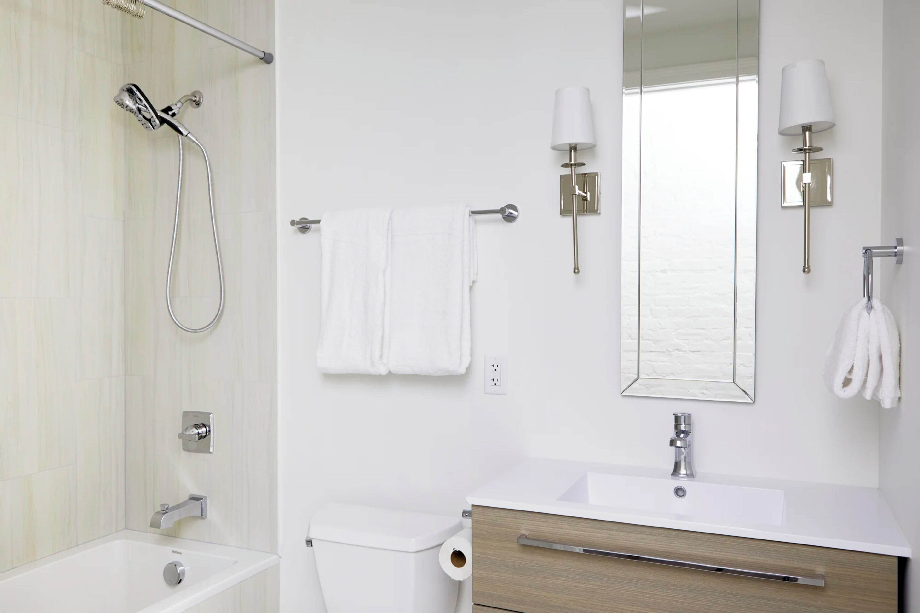 A modern bathroom with a shower, toilet, sink, and towel rack.