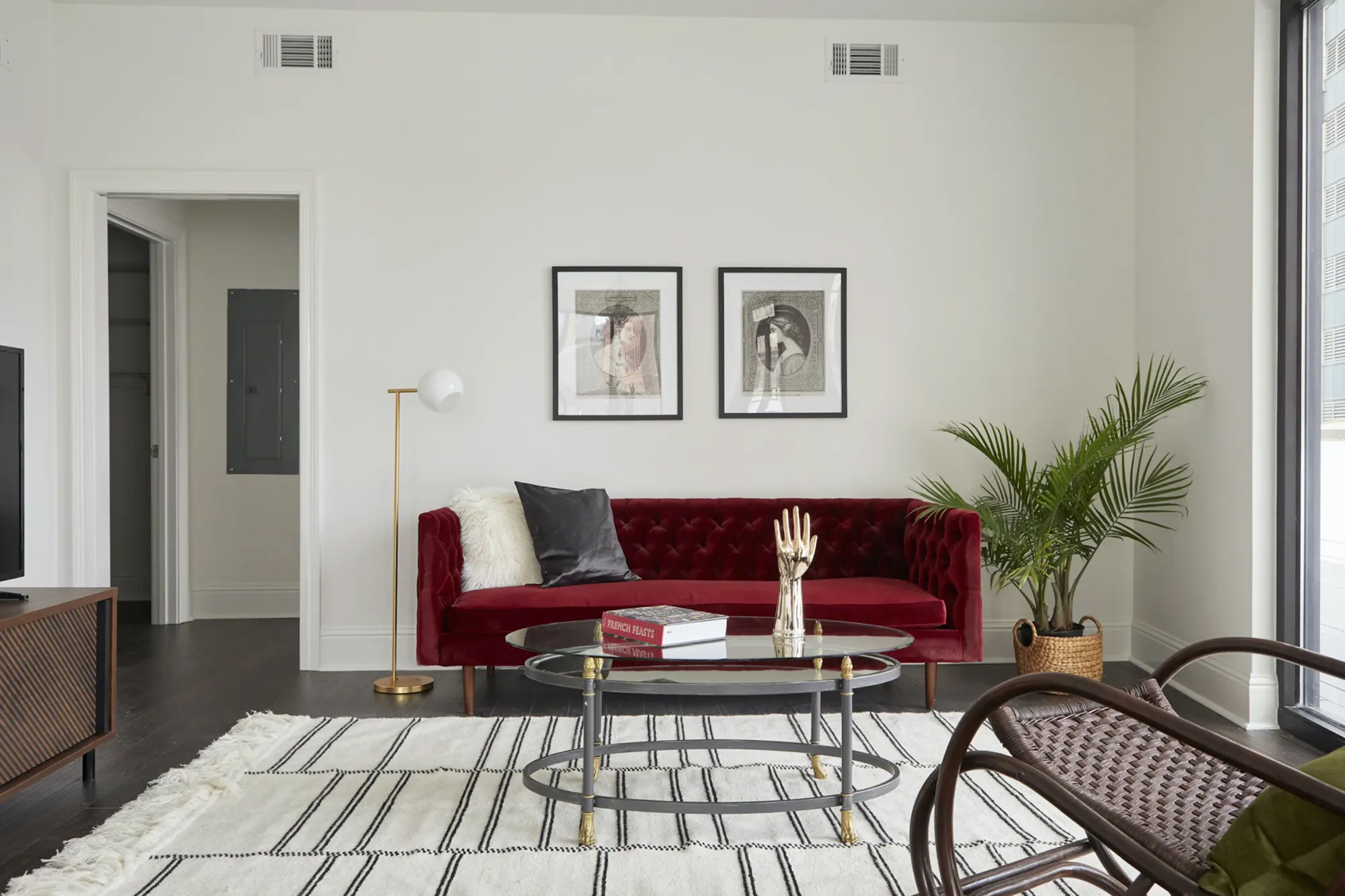 A modern living room with a red sofa, a glass coffee table, and a potted plant.