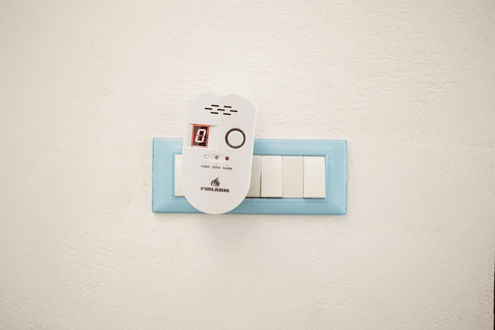Un détecteur d’incendie numérique blanc, fixé sur un mur bleu clair.