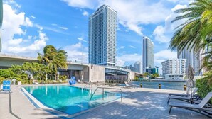 A swimming pool with lounge chairs and palm trees, surrounded by high-rise buildings. - Luxury Waterfront Suite with Great Views (Hallandale Beach)