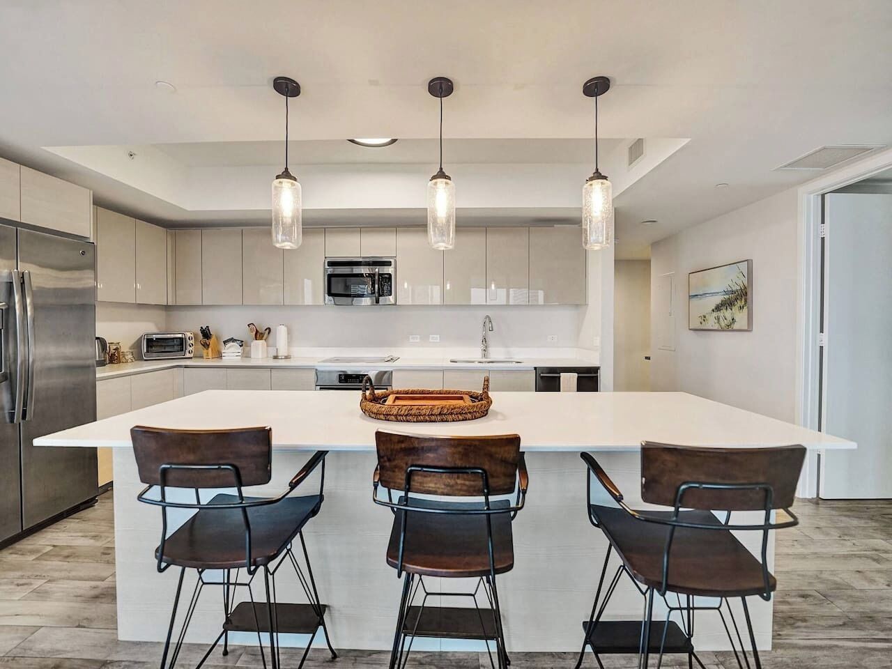 A modern kitchen with a central island, stainless steel appliances, and pendant lighting.