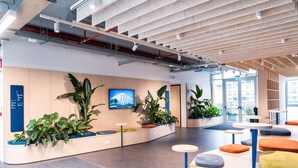 A modern interior with a reception desk, potted plants, and colorful seating areas. - aparto Milan Ripamonti (Milan)