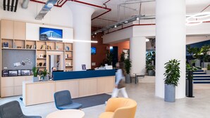 A modern reception area with a counter, seating, and potted plants. - aparto Milan Ripamonti (Milan)