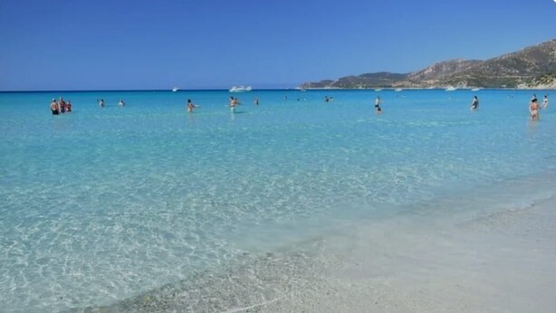 A beach with clear turquoise water and a sandy shore.
