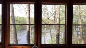 A room with large windows overlooking a forest and a body of water.