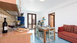 Una cocina compacta con comedor, un sofá rojo y un televisor.
