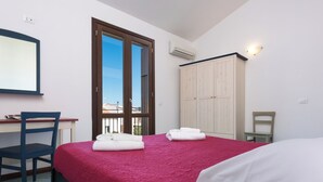 Un dormitorio con cama, escritorio, silla, armario y ventana.
