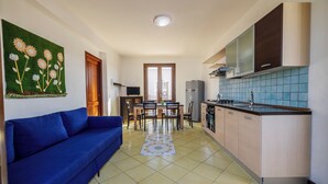 Una cocina moderna con comedor, un sofá azul y un adorno de pared.