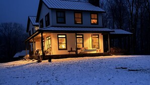Una casa de dues plantes amb un porxo, entrada coberta i pati cobert de neu.