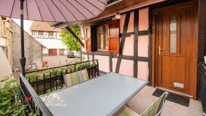 Un bâtiment de style européen traditionnel, doté d’une porte en bois, d’un balcon avec une table et des chaises, et d’un grand parasol.