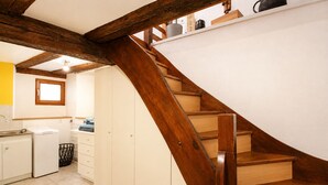 Une cuisine avec un escalier en bois, des placards blancs et une fenêtre.