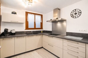 Een moderne keuken met een ingebouwde oven, een roestvrijstalen afzuigkap, een dubbele spoelbak en een klok aan de muur.