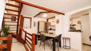 Un espace repas avec un escalier en bois, une cuisine à l’arrière-plan et un petit coin bar.