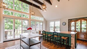 A spacious kitchen with large windows, wooden floors, and a bar area.