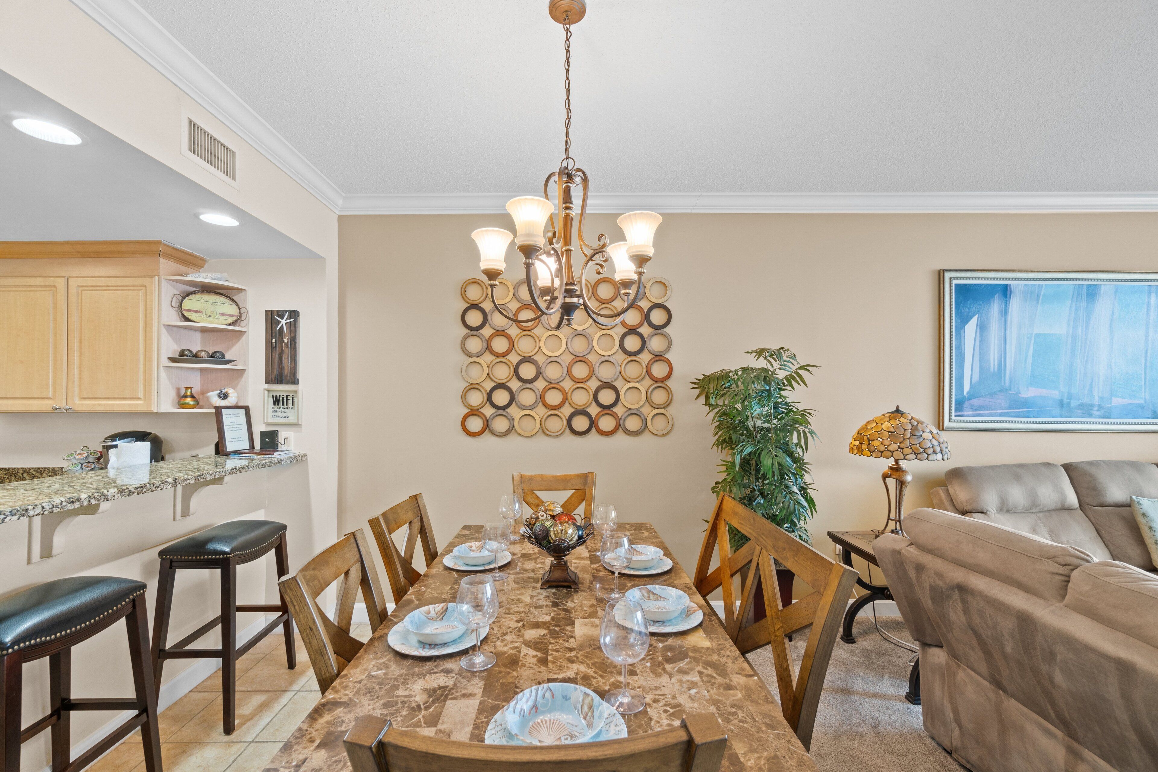 A dining area with a marble table, wooden chairs, and a chandelier.