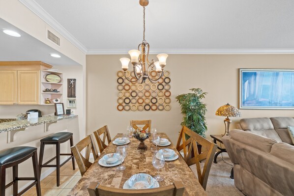 A dining area with a marble table, wooden chairs, and a chandelier.