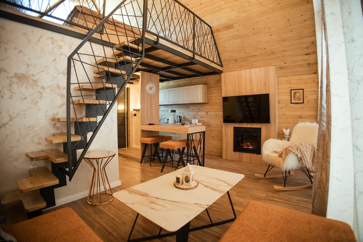 A modern interior with a wooden staircase, a kitchen area, a fireplace, and a cozy seating area.