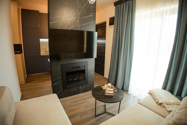 Un salon moderne avec une cheminée, un canapé, une table basse et une cuisine en arrière-plan.