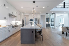 A modern kitchen with a central island, stainless steel appliances, and a pendant light. - Scenic Hollows Escape with Trails & Outdoor Fun (Jonestown)
