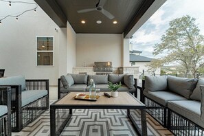 An outdoor patio area with a ceiling fan, a grill, and seating arrangements. - Scenic Hollows Escape with Trails & Outdoor Fun (Jonestown)