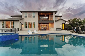 A modern two-story house with a swimming pool, outdoor seating, and a well-lit entrance. - Scenic Hollows Escape with Trails & Outdoor Fun (Jonestown)