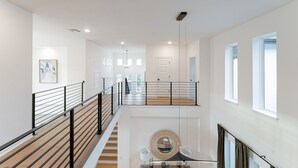 A modern interior with a wooden staircase, a round mirror, and a minimalist design. - Luxury Meets Nature at The Hollows: Scenic Trails, Pools & Premium Vacation Home (Jonestown)