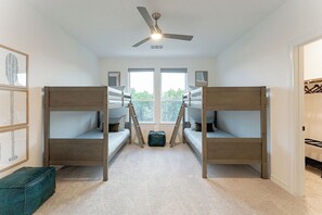Een kamer met stapelbedden, een plafondventilator en een groot raam.