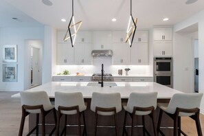 A modern kitchen with a central island, bar stools, and pendant lighting. - Scenic Hollows Escape with Trails & Outdoor Fun (Jonestown)
