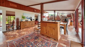 Een ruime woonkamer met een houten eettafel, een keukeneiland en een groot vloerkleed.