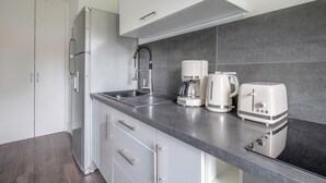 A modern kitchen with a stainless steel refrigerator, a coffee maker, a toaster, and a sink.