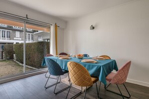 Un comedor con una mesa dispuesta para cuatro personas, un ventanal y vistas a un edificio residencial.