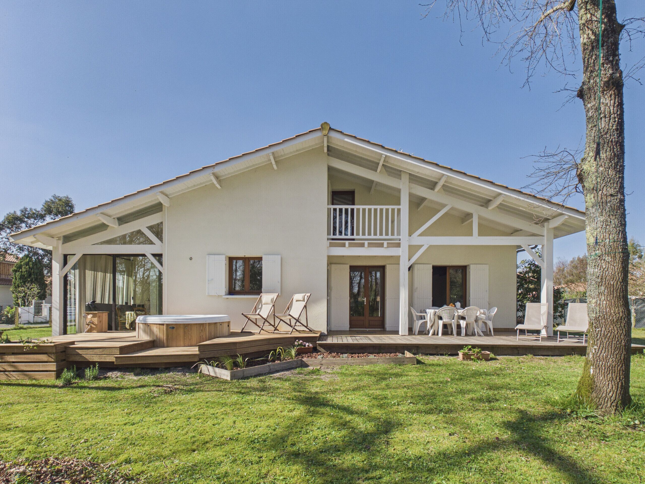 Ein zweistöckiges Haus mit Balkon, Whirlpool und Sitzgelegenheit im Freien.