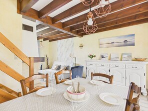 A dining area with a wooden ceiling, white walls, a marble backsplash, and a dining table set for four.