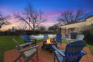 A backyard with a fire pit, outdoor seating, and a barbecue area. - Crystal Cow Haus Luxury Home-Pool-HotTub-Near Main (Fredericksburg)