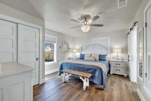 A bedroom with a bed, bedside tables, a bench, and a ceiling fan. - Crystal Cow Haus Luxury Home-Pool-HotTub-Near Main (Fredericksburg)