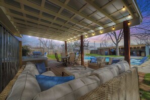 Un patio al aire libre con zona de estar cubierta, piscina y zona de barbacoa.