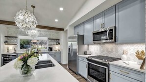 Una cocina moderna con armarios grises, electrodomésticos de acero inoxidable y una isla central con un jarrón de flores.