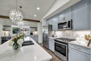 Une cuisine moderne avec des meubles gris, des appareils en acier inoxydable et un îlot central agrémenté d’un vase de fleurs.