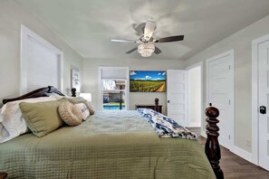 A bedroom with a large bed, a ceiling fan, and a view of a vineyard through an open door. - Crystal Cow Haus Luxury Home-Pool-HotTub-Near Main (Fredericksburg)