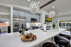 Una cocina moderna con una isla grande, electrodomésticos de acero inoxidable y una araña.