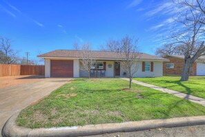 A single-story house with a garage, a small front yard, and a tree. - Crystal Cow Haus Luxury Home-Pool-HotTub-Near Main (Fredericksburg)