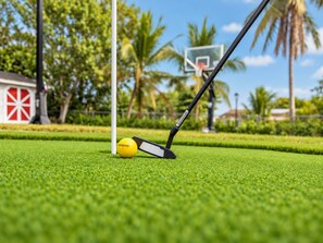 A golf ball on artificial grass with a golf club in the foreground.