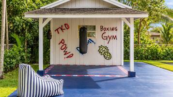 A small building with 'Boxing Gym' written on the side, a punching bag, and a blue mat with red and white markings.